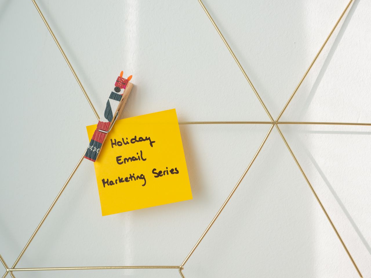 Services-01 Bright yellow sticky note with holiday email marketing message clipped to a wireframe wall.