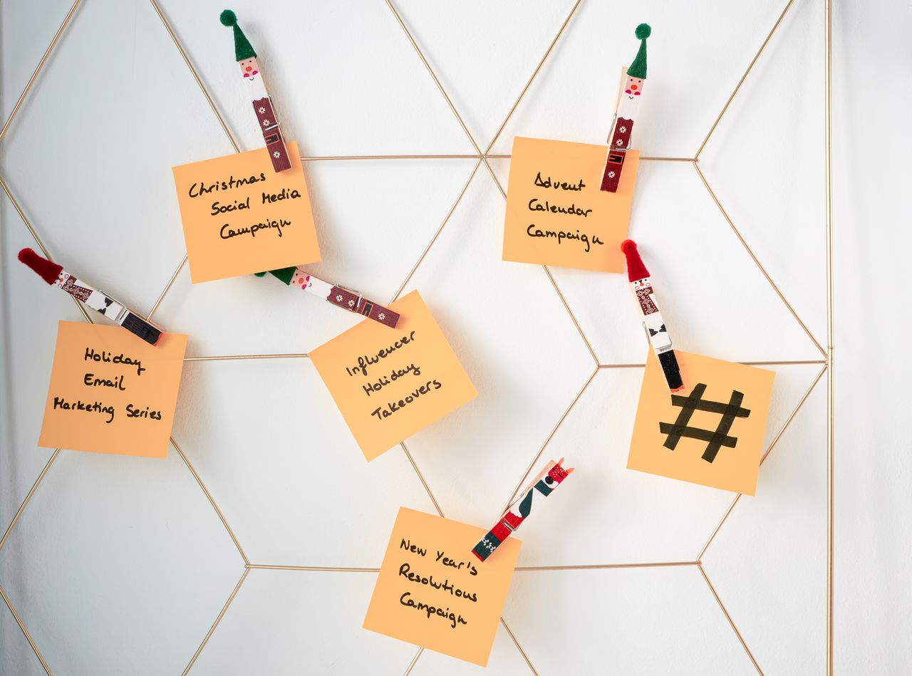 digital Sticky notes with holiday marketing ideas clipped to a wall grid.